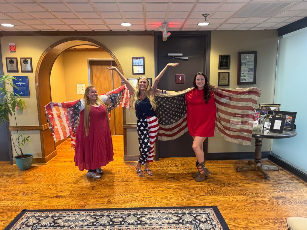 Team members posing in office with flag display